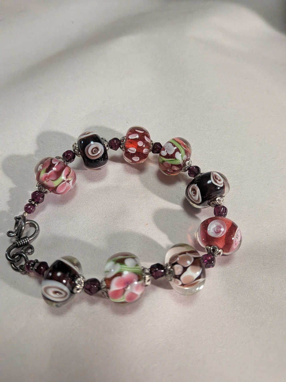 handmade bracelet features lampwork glass beads in reds/Purples 925 Clasp